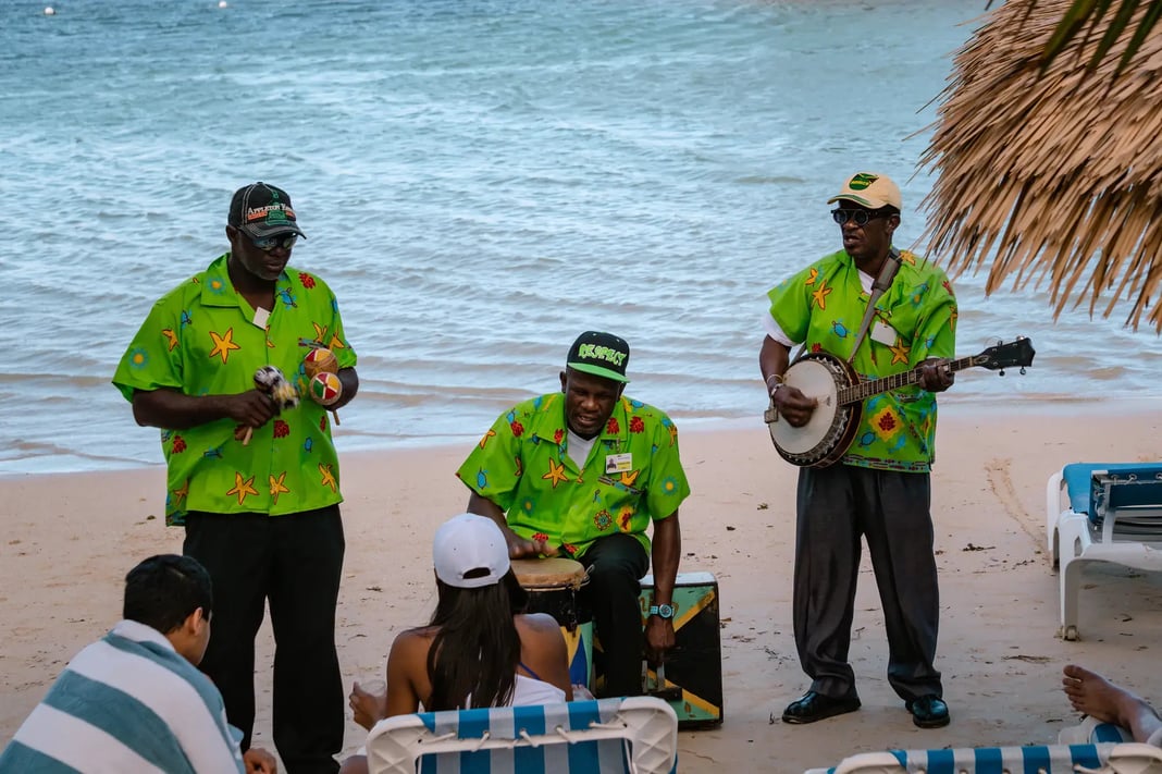 Beachside band performing with drums and banjo for guests near the shoreline